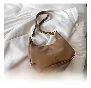 Close-up of retro brown faux leather dumpling bag with elegant gold metal adjustment buckle