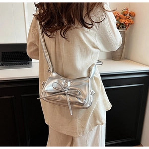 Sac bandoulière argenté en PU avec nœud papillon porté par un mannequin au bureau