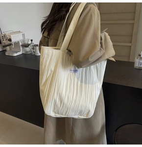Detailed shot of a white quilted tote bag with a Kiss Yourself label in a modern cafe setting