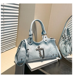 Detail of light blue motorcycle bag with metal cross charm and silver rivets