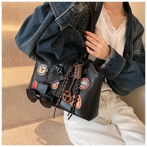 Détail du sac à bandoulière noir vintage avec badges élégants et pendentifs