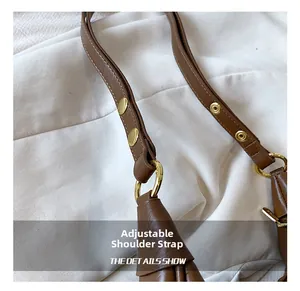 Detail of adjustable litchi grain leather strap with gold buckle on a brown bag
