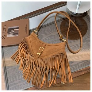 Détail d'un sac demi-lune en daim marron avec de longues franges et une boucle dorée