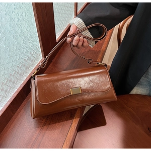 Detail of a brown vintage leather shoulder bag with a sleek oily texture and gold buckle