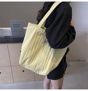 Detail of a pleated canvas tote bag with side label and long shoulder straps