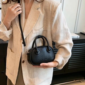 Dettaglio mini borsa nera con attacco manico a cuore e goffratura fashion moderna