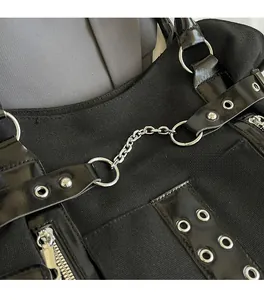 Detail view of black canvas tote with metallic chains and smooth synthetic leather straps