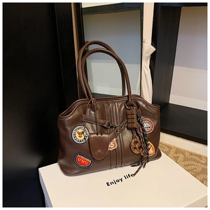 Détail macro du sac cabas en cuir marron foncé avec écussons vintage américains