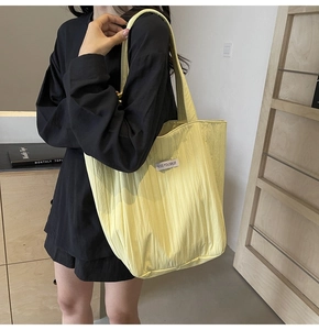 Detailed view of the yellow pleated canvas tote bag with textured quilting and brand tag