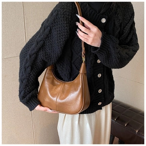 Detail view of brown glossy leather crescent bag with adjustable golden buckle