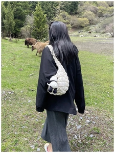 Quilted white puffer shoulder bag with a cute panda pendant shown in an outdoor setting