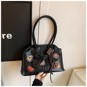 Détail du sac cabas en PU noir avec des écussons brodés colorés et des breloques de sac