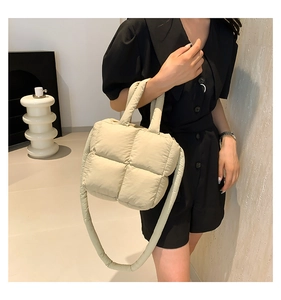 Vue détaillée du sac bandoulière matelassé beige avec bandoulière rembourrée sur un modèle