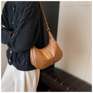 Brown semi-circle leather underarm bag featuring adjustable strap and gold metal hardware