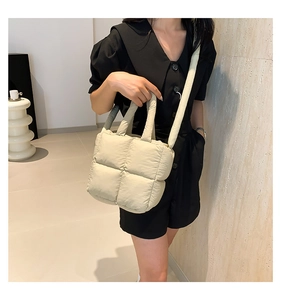 Détail de la texture matelassée du sac bandoulière beige et de la bandoulière souple