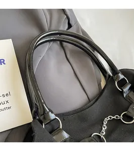 Close-up of canvas tote bag showing glossy handles with silver rings and chain details