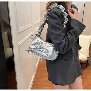 Sac à bandoulière argenté métallisé avec nœud et bandoulière plissée sur un mannequin