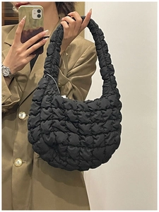 Close-up of black quilted puff shoulder bag featuring soft textured padded fabric