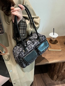 Leopard print bowling bag with black leather handles shown in a lifestyle street setting