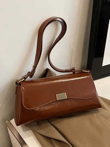 Vintage caramel brown leather shoulder bag with gold buckle on a neutral background