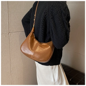 Brown vintage half-moon hobo bag worn by model over a black knitted sweater
