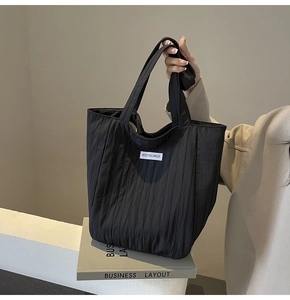 Close-up of black pleated tote bag with Kiss Yourself patch on soft fabric