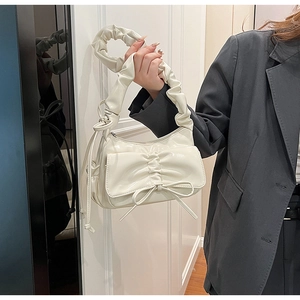 Détail du sac à bandoulière en similicuir crème avec anse plissée et nœud élégant