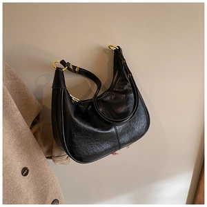 Detail of glossy black hobo bag with gold hardware and vintage oily leather texture