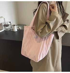 Detail view of pink pleated tote bag showing waterproof nylon texture and woven label