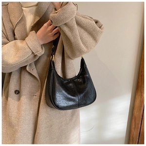 Detail view of the black hobo bag's pleated leather texture and gold metallic hardware