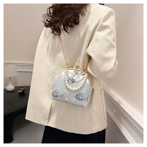 Detalle del bolso bordado de estilo vintage con asa de perlas grandes y una cadena dorada