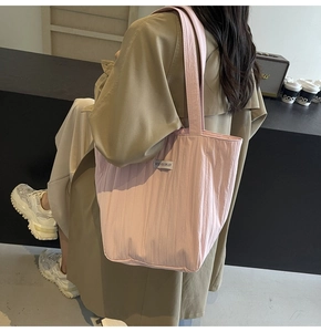 Close-up of pink quilted tote bag with vertical stripes and stylish fabric brand label