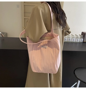 Pink pleated canvas tote bag detail with Kiss Yourself label on woman's shoulder