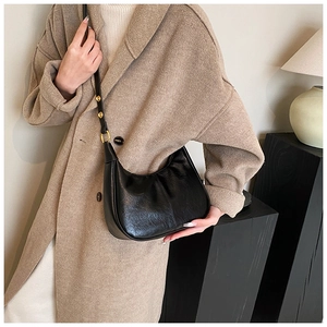 Detail of black crescent shoulder bag with vintage pleated texture and gold hardware