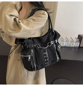 Gothic punk black canvas tote bag with metal eyelets and chains styled on a trench coat