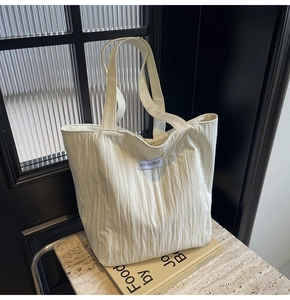 Close-up of cream pleated canvas tote bag with woven label on a lifestyle background