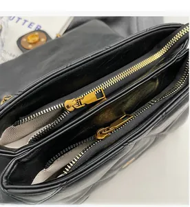 Gros plan du sac matelassé noir avec double fermeture éclair dorée et doublure interne