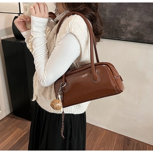 Detail of glossy brown faux leather shoulder bag featuring a cute cookie charm accessory