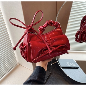 Vue détaillée du sac à main rouge en cuir verni avec nœud géant et anse plissée