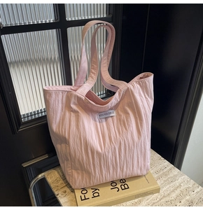 Detailed view of pink quilted tote bag with pleated texture and white fabric label