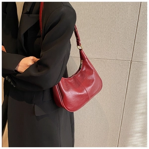 Detail of a burgundy crescent hobo bag with vintage crinkle texture and gold hardware zipper