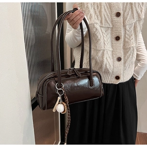 Detail view of brown vintage baguette bag with contrast stitching and baseball charm