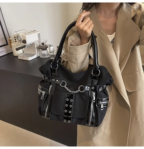 Detail of black punk tote bag with silver chains, rivets and functional zippers