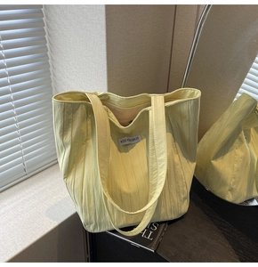 Detail shot of vertical pleated canvas texture and minimalist brand label on tote bag