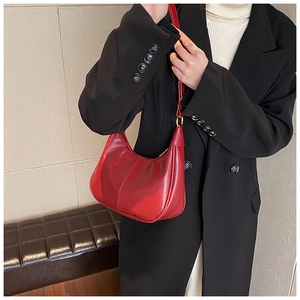Detail of red crescent shoulder bag with glossy leather and gold buckle hardware