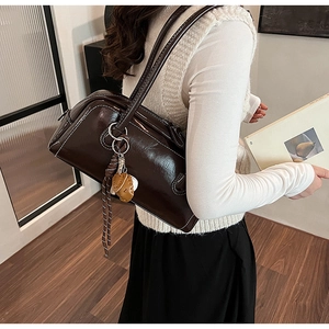 Close-up of dark brown glossy leather baguette bag with white contrast stitching details