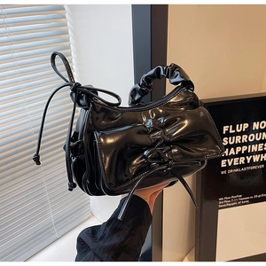Détail du sac en cuir verni noir brillant avec une décoration de nœud plissé chic
