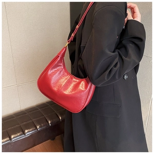 Close-up of vibrant red leather crescent hobo bag with adjustable strap and gold hardware