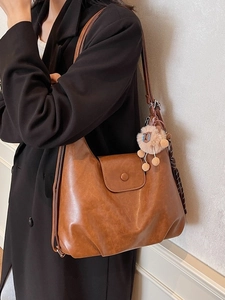 Brown vintage faux leather tote bag for women with lion pendant shown on a model
