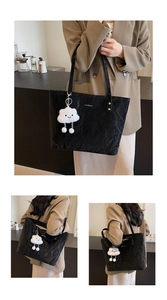 Detail of black pleated tote bag featuring a metal trim and white cloud plush charm